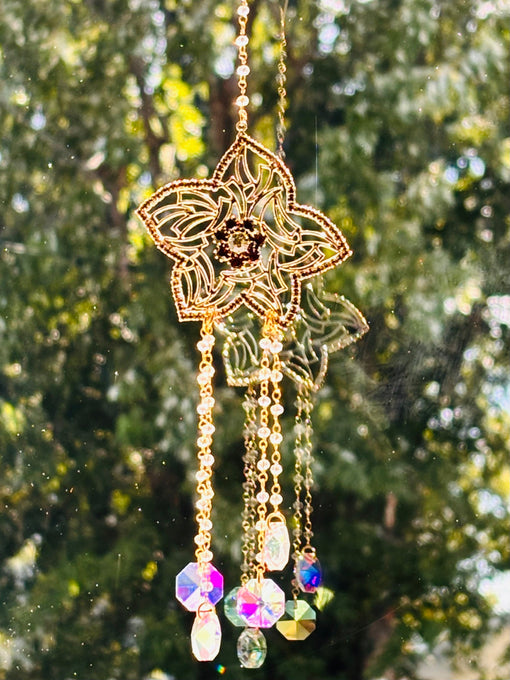Winter’s Gold suncatcher with golden flower detailing and hanging iridescent crystals in sunlight