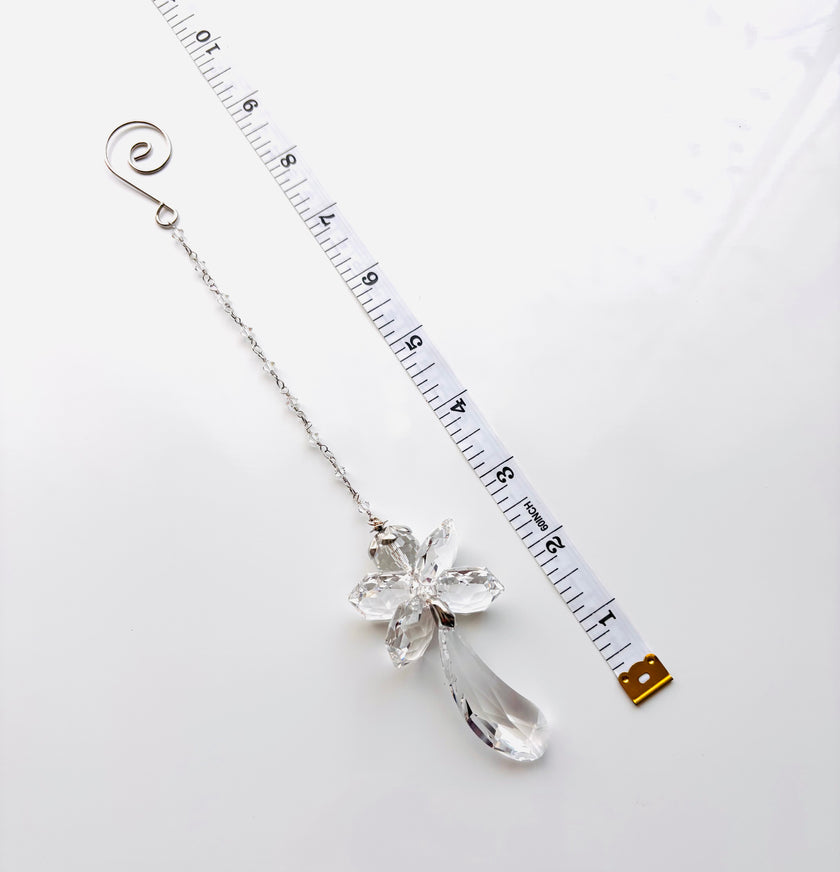 A silver-toned crystal fairy angel with a teardrop crystal pendant and a spiral end, shown next to a measuring tape on a white background.