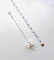 A silver chain accessory with a spiral clasp and a dangling iridescent butterfly charm, shown on a white background with a measuring tape and small gold tag nearby for scale.