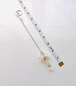 A silver-toned crystal angel with a spiral end and a dangling faceted crystal charm, shown next to a white measuring tape on a light background.
