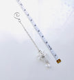 A silver beaded chain with a clear crystal angel shown next to a white measuring tape to indicate its length.
