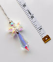 An iridescent crystal angel on a silver chain, shown next to a white measuring tape to indicate its size.