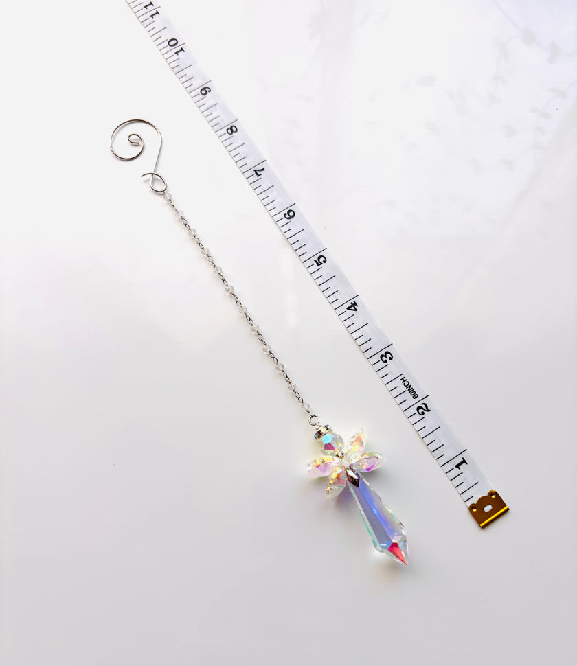 A silver beaded chain with a crystal angel and a spiral end, shown on a white background next to a measuring tape for scaled.