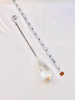 A clear faceted crystal suncatcher with a silver chain and spiral top, shown next to a measuring tape to indicate its size on a white background.