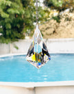 A large faceted clear crystal suncatcher hanging from a silver beaded shimmering with colors in a bright window.