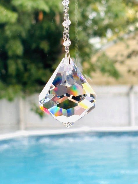 Diamond shape Crystal SUNCATCHER with rays of color shimmering in a bright window.
