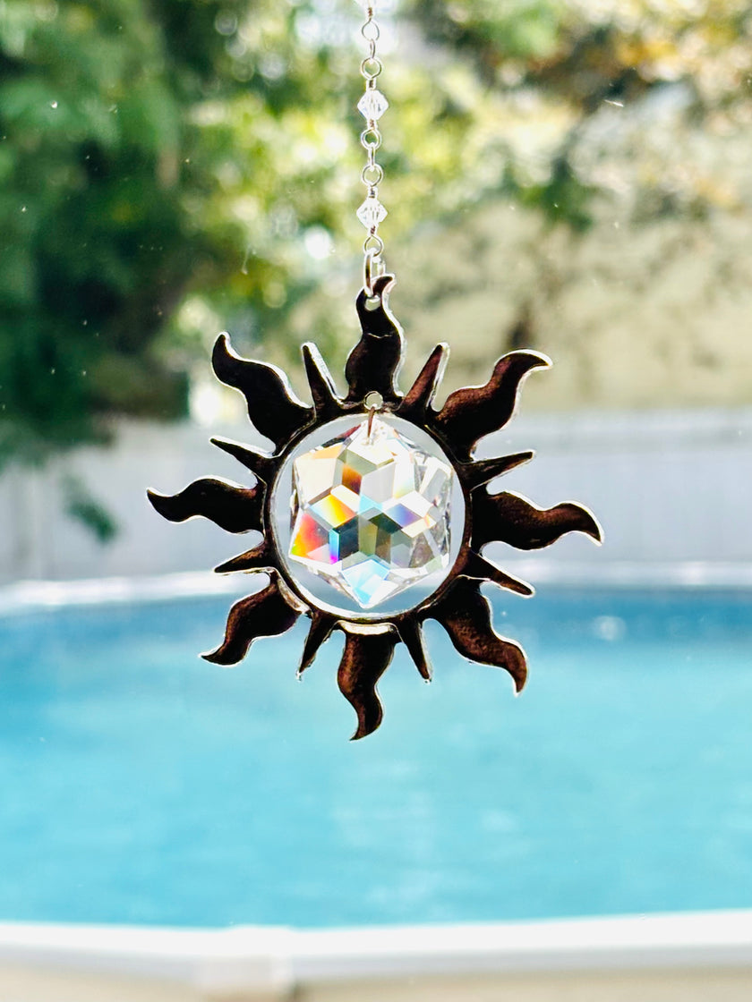 Sun shaped crystal prism SUNCATCHER with wavy rays and Swarovski hex star inside showing stunning colors from window.