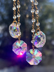 Close-up of the Winter's Gold suncatcher showcasing faceted octagonal crystal prisms catching the light with a vibrant iridescent purple and pink rainbow shimmer.