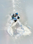 Diamond like suncatcher featuring a silver flower and portraying glowing rainbows around it. 