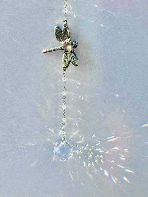 Damselfly adorned with clear Swarovski crystal ball creating prisms of rainbows. 