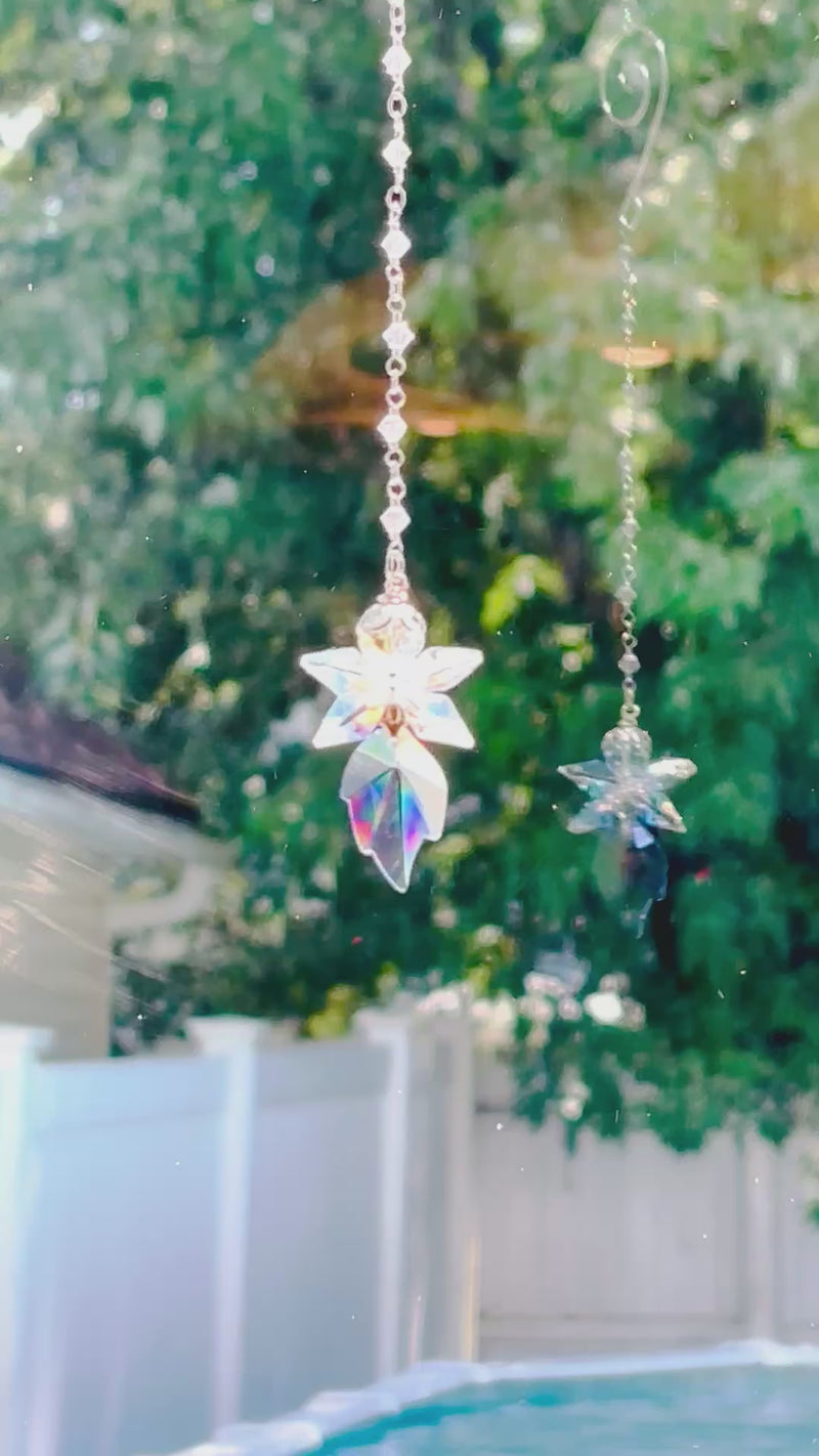 A beautiful blue fairy spinning in a bright window casting rainbows and reflection. 