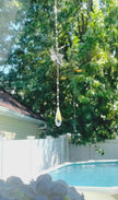 A dragonfly suncatcher with a colorful Swarovski crystal sparkling as it is spinning in a bright window casting its own reflection.