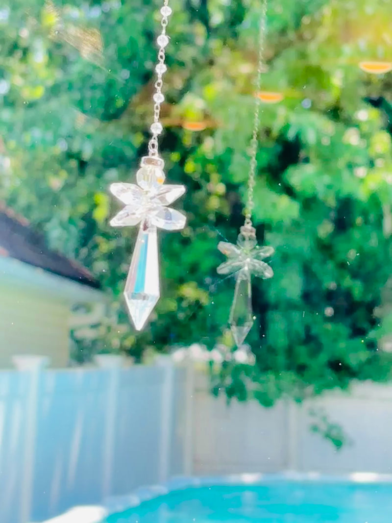 A clear crystal angel casting sparkles and reflection in a bright window. 