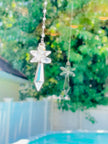 A clear crystal angel casting sparkles and reflection in a bright window. 