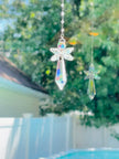 A colorful aurora borealis angel suncatcher sparkling as it spins in a bright window.