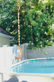 A gold crystal suncatcher with a aurora borealis heart and beaded chain spinning in a bright window.