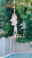 A artistic fairy angel suncatcher casting rainbows and reflection as it spins in a bright window.
