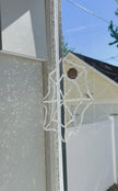 Video preview of the hand-beaded crystal spiderweb suncatcher hanging in a sunny window frame. Direct sunlight hits the 448 iridescent bicone glass crystals, casting a dense, shimmering burst of hundreds of brilliant rainbows across the indoor wall.