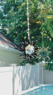 A sun shaped suncatcher with a colorful Swarovski crystal sparkling as it is spinning in a bright window casting its own reflection.